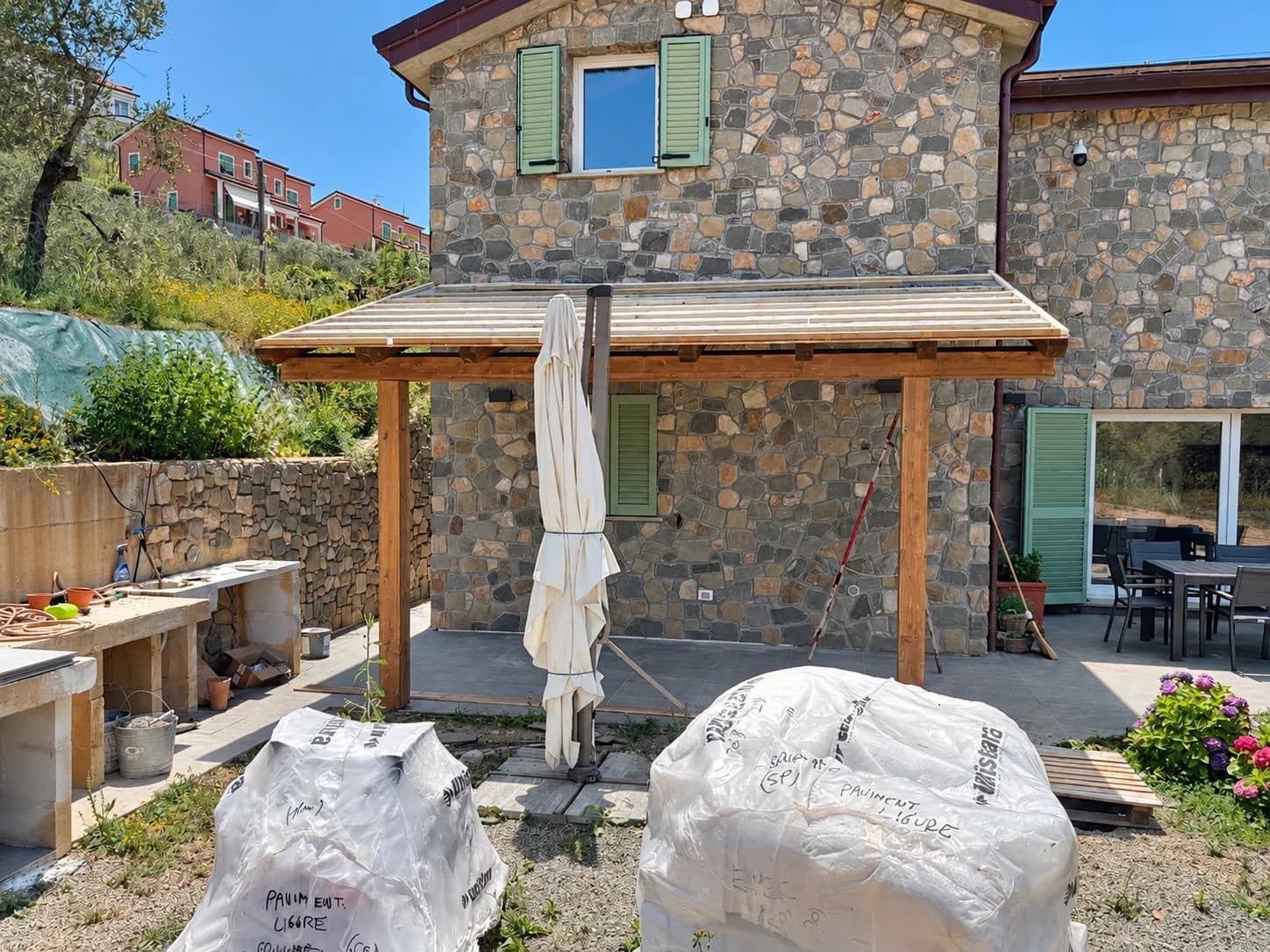 Casa in pietra con persiane verdi e portico in legno